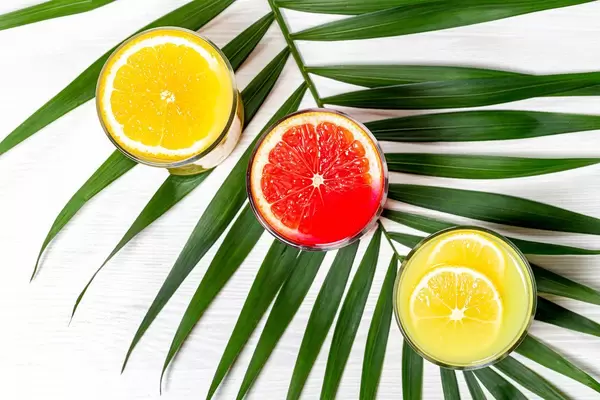 Top view glasses with lemon, orange and grapefruit juice with green leaf (Flip 2019)