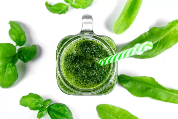 Top view, green smoothie with fresh leaves on a white background. Healthy food concept