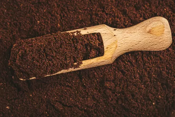 Top view, ground coffee in wooden scoop