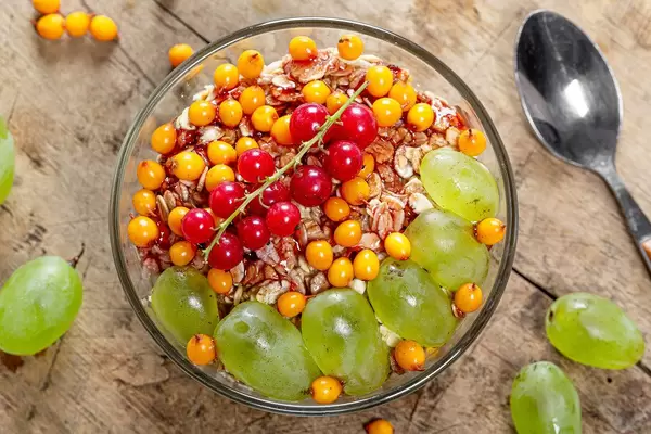 Top-view Haferflocken Brei mit frischen Sanddorn Beeren, roten Johannisbeeren und Trauben