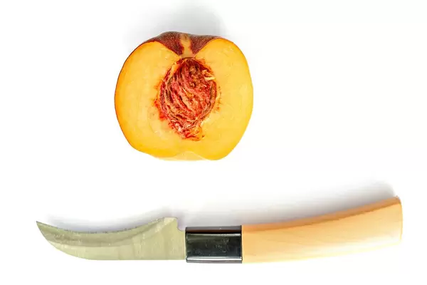 Top view, half of ripe peach with a knife