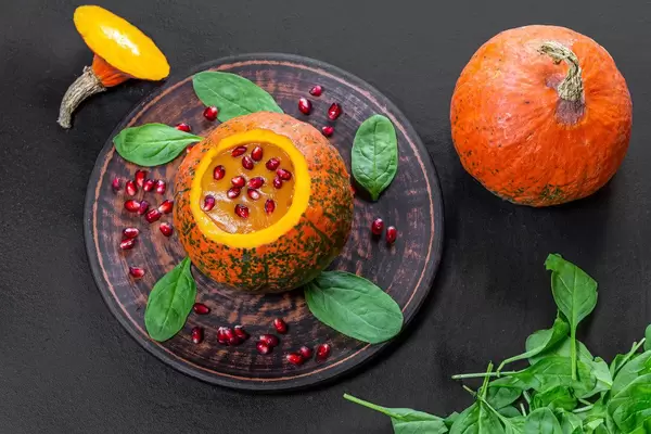 Top view Halloween concept-pumpkin with pumpkin puree, spinach and pomegranate on black background (Flip 2019)