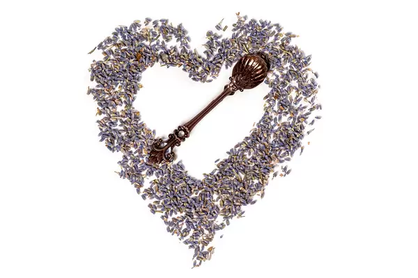 Top view, heart made of lavender flowers on white with teaspoon