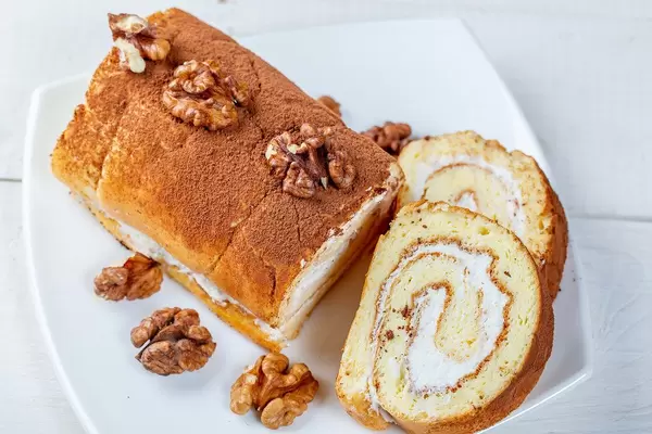 Top view homemade biscuit roll with cream and walnuts
