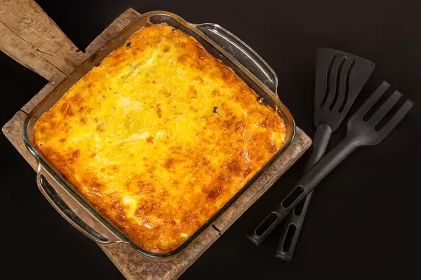Top view, homemade casserole with chicken fillet, mushrooms and cheese in glass baking sheet