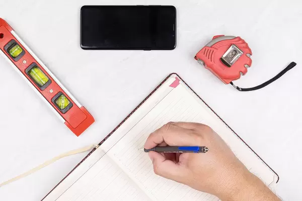 Top view Level Measure Tape Mobile phone Hand with Pencil and Paper Notebook