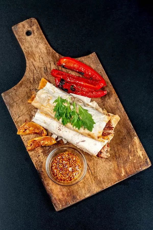 Top view, lula kebab in pita bread and grilled vegetables on an old wooden kitchen board