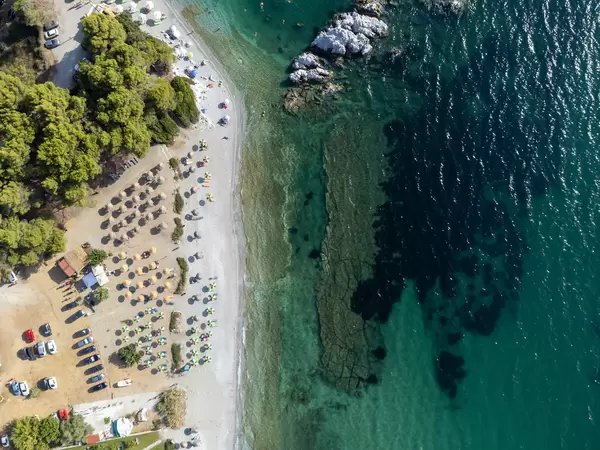 Top view: Milia beach on Skopelos with turquoise water and straw and blue-yellow parasols