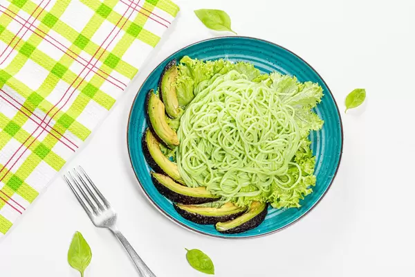 Top-view Nahaufnahme von grünen Spaghetti, Avocado Scheiben, Basilikum und Salat