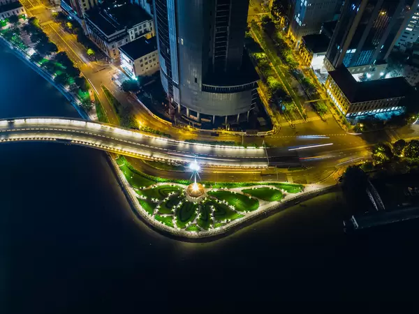 Top View Night Photo of Thu Ngu Flagpole with a Park in Flower Design next to Saigon One at Saigon River in Ho Chi Minh City, Vietnam