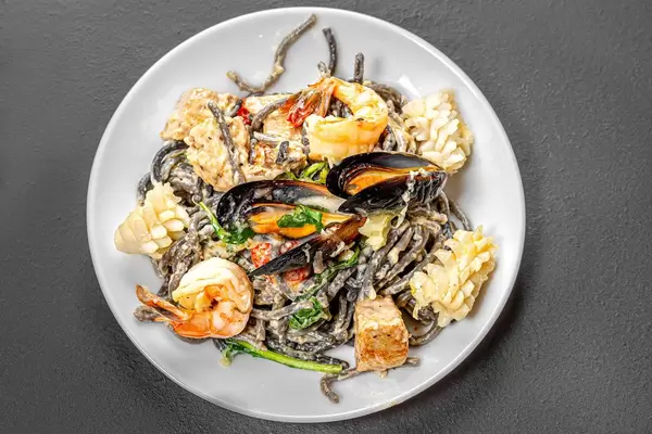 Top view noodles with cuttlefish ink in creamy sauce with seafood (Flip 2019)