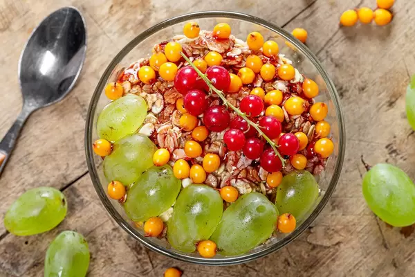 Top view oatmeal porridge with fresh sea buckthorn berries, red currants and grapes (Flip 2019)
