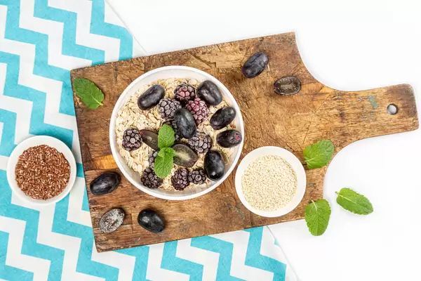 Top view, oatmeal with blueberries and grapes on an old board with fresh mint leaves and seeds