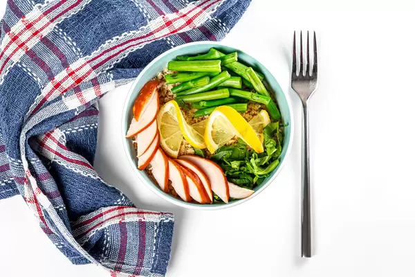 Top view, oatmeal with chicken pieces, broccolini, spinach and lemon