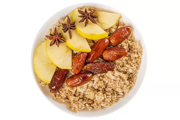 Top view, oatmeal with dates and apple on a white background