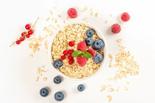 Top view, oatmeal with strawberries, red currant blueberries and mint leaves