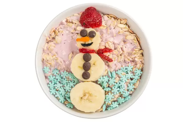 Top view, oatmeal with strawberry yogurt and banana snowman