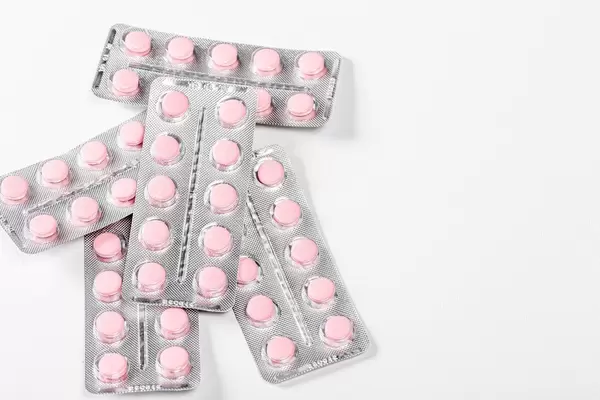 Top view of a blister with pink pills on a white background (Flip 2019)