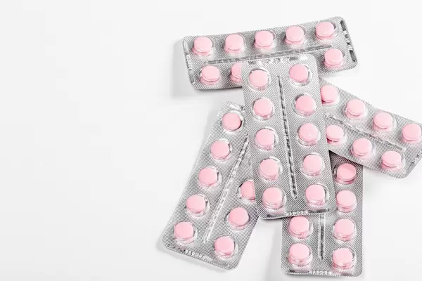 Top view of a blister with pink pills on a white background