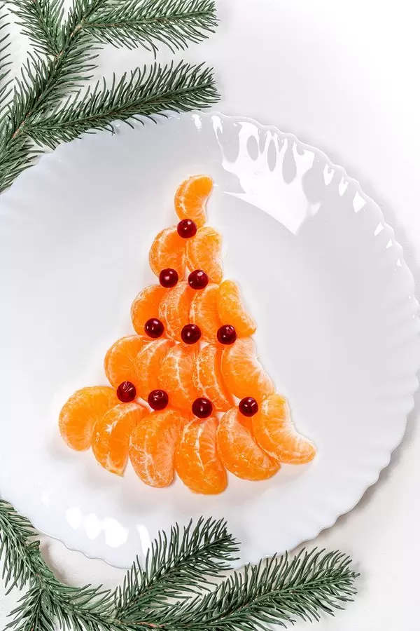 Top view of a Christmas tree made from mandarin and cranberries on a white plate (Flip 2019)