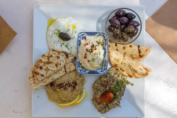 Top view of a dips Plate with pita bread, tzatziki, fresh roe dip, aubergine salad, hummus, pita bread and olives