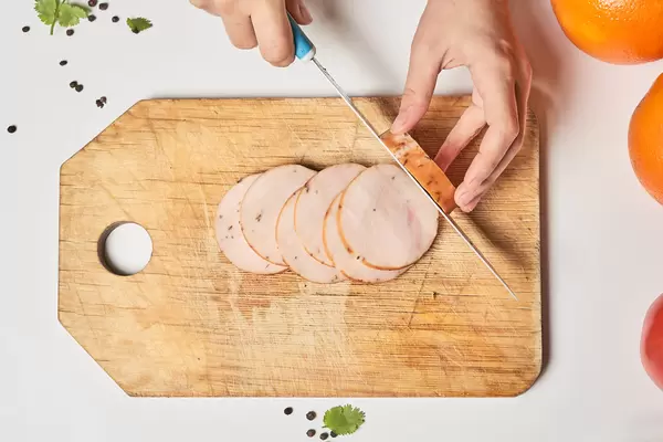 Top view of a female cutting delicious smoked chicken meat
