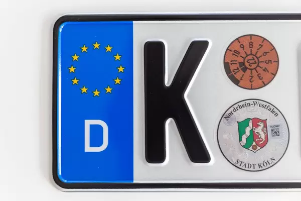 Top view of a German license plate of Cologne, with European stars, on a white surface