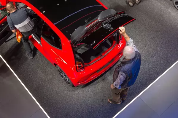 Top view of a red VW Up! GTI: Man opens the trunk with roof spoiler