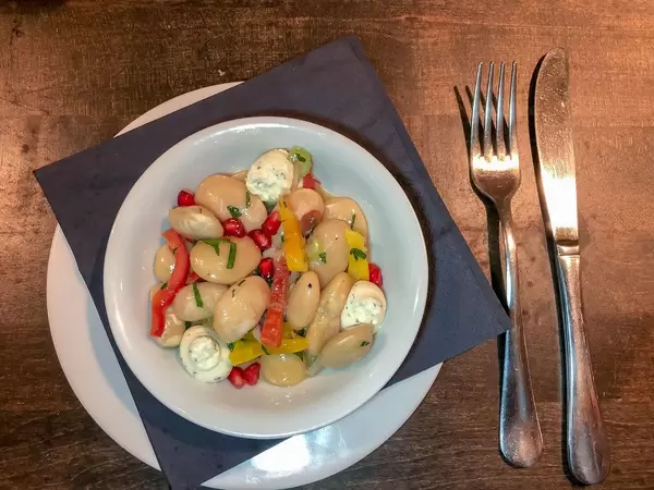 Top view of a salad with elephant beans, pomegranate and cream made of goat milk cheese