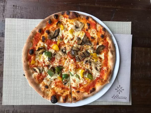 Top view of a vegetarian Pizza with vegetables and mushrooms, cut in slices