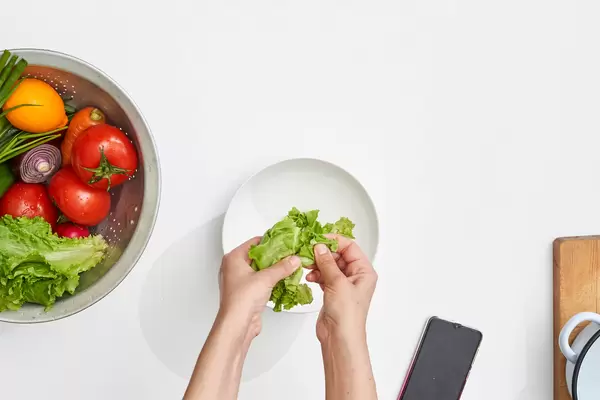 Top view of a woman hand preparing a fresh vegetarian salad with organic vegetables