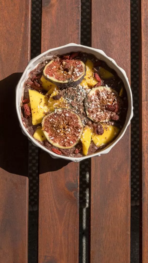 Top view of an Acai Bowl with mango, figs, raisins, goji berries and shredded coconut
