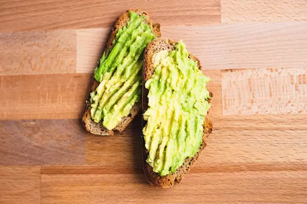 Top view of avocado on rye bread toast on wooden board