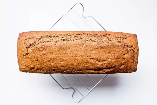 Top view of banana bread loaf on cooling rack on white background