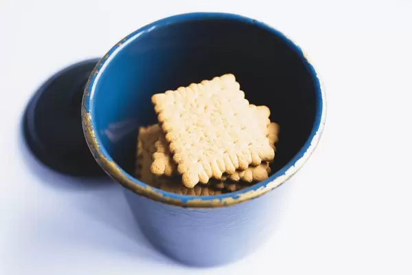 Top view of biscuits in a metal jar on white background