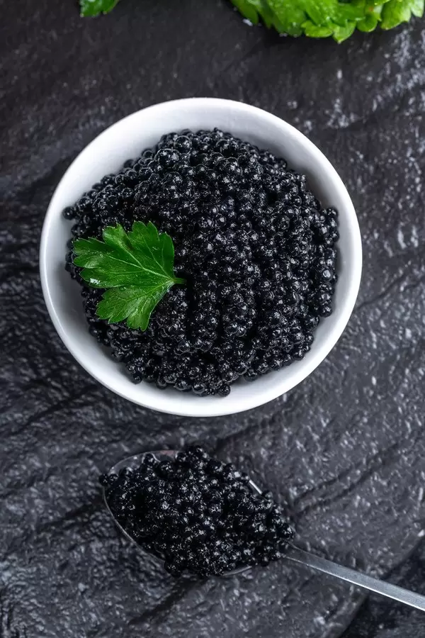 Top view of black caviar in the gravy boat and spoon (Flip 2019)