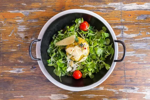 Top view of black pan on an old wooden table with a pumpkin Knödel (Alpine dumpling) at Dauerstoa Alm