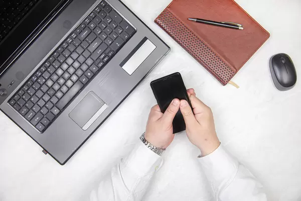 Top view of businesman holding mobile phone on the desk