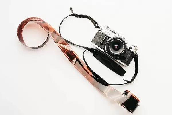 Top view of Canon AE-1 film camera with developed film on white background