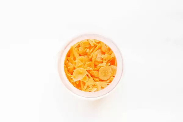 Top view of chopped carrots in jar on white background