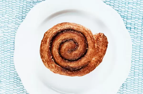 Top view of cinnamon roll in white plate.