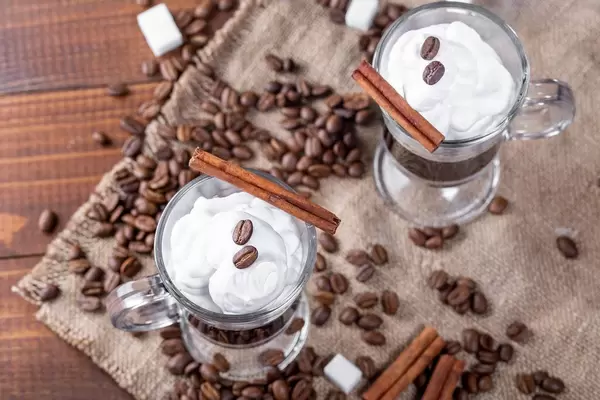 Top view of coffee with cream, coffee beans and spices on burlap