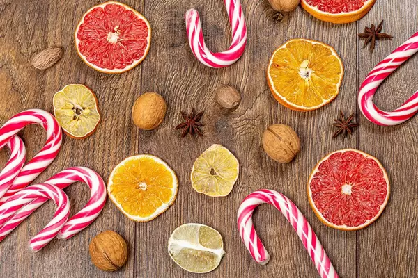 Top view of dried slices of citrus fruit, nuts, and candy cane on wooden background (Flip 2019)