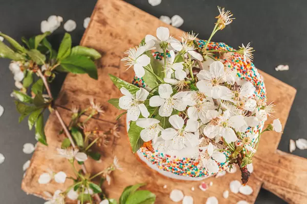 Top view of easter cake decorated with cherry flowers on wooden board