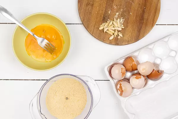 Top view of Egg mixture with Egg Shells in the box and grated Almonds