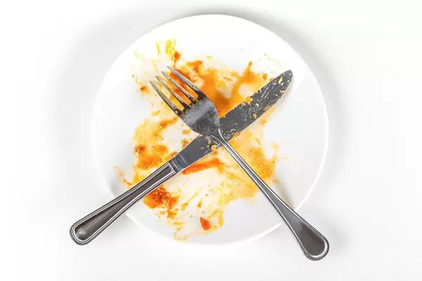 Top view of empty plate with fork and knife, dirty after the meal is finished