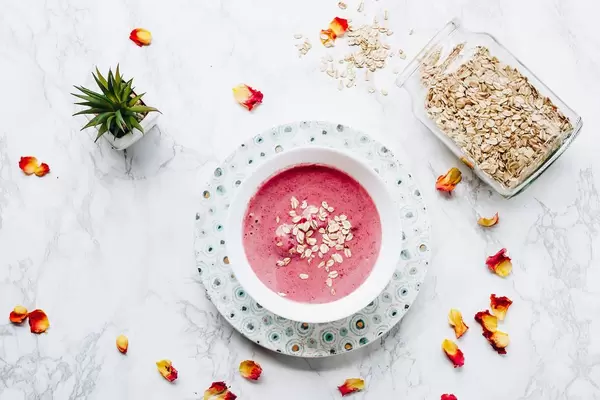 Top view of flat lay with healthy smoothie, oat flakes and a plant. Marble background