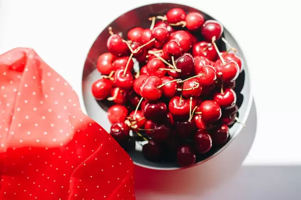 Top view of fresh cherries in a bowl with red fabric