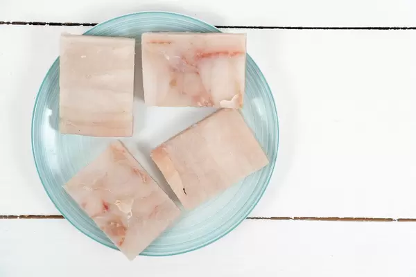 Top view of Frozen Alaska Pollock fish on the plate ready for frying (Flip 2020)