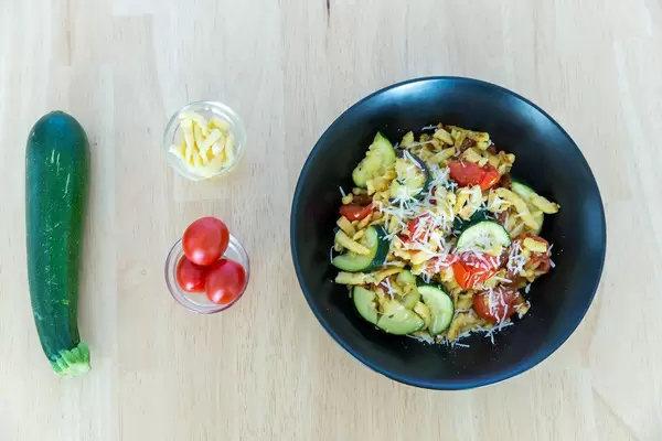 Top view of golden brown roasted spaetzle with dried tomatoes and zucchini including ingredients